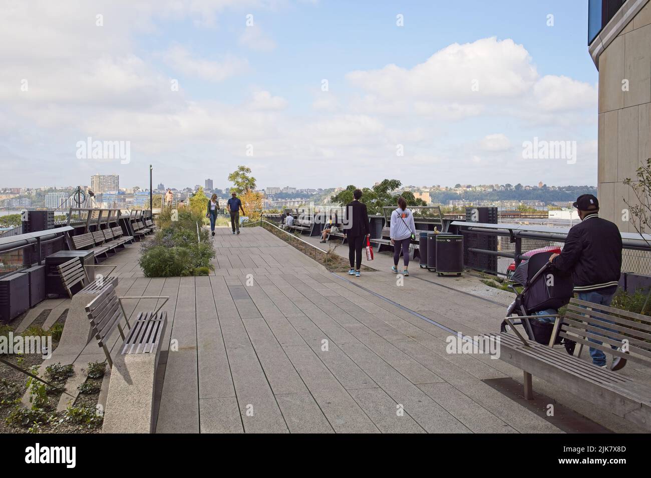 New York, NY, USA - 1 agosto 2022: Persone che camminano sulla High Line sopra 30th Street guardando verso ovest verso lo skyline del New Jersey Foto Stock