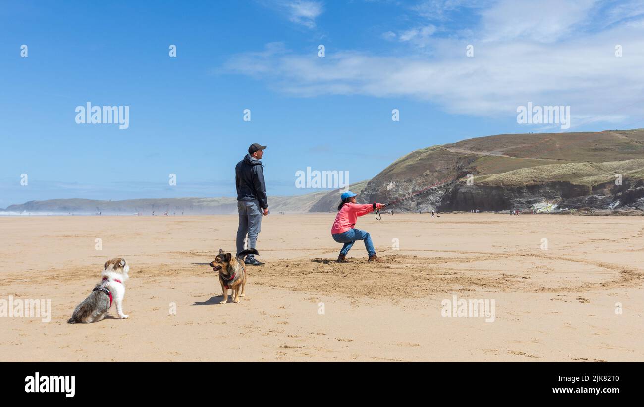 Una donna si oppone al potere del suo allenatore kite come il suo partner guarda e dà consigli. Due cani in primo piano Foto Stock