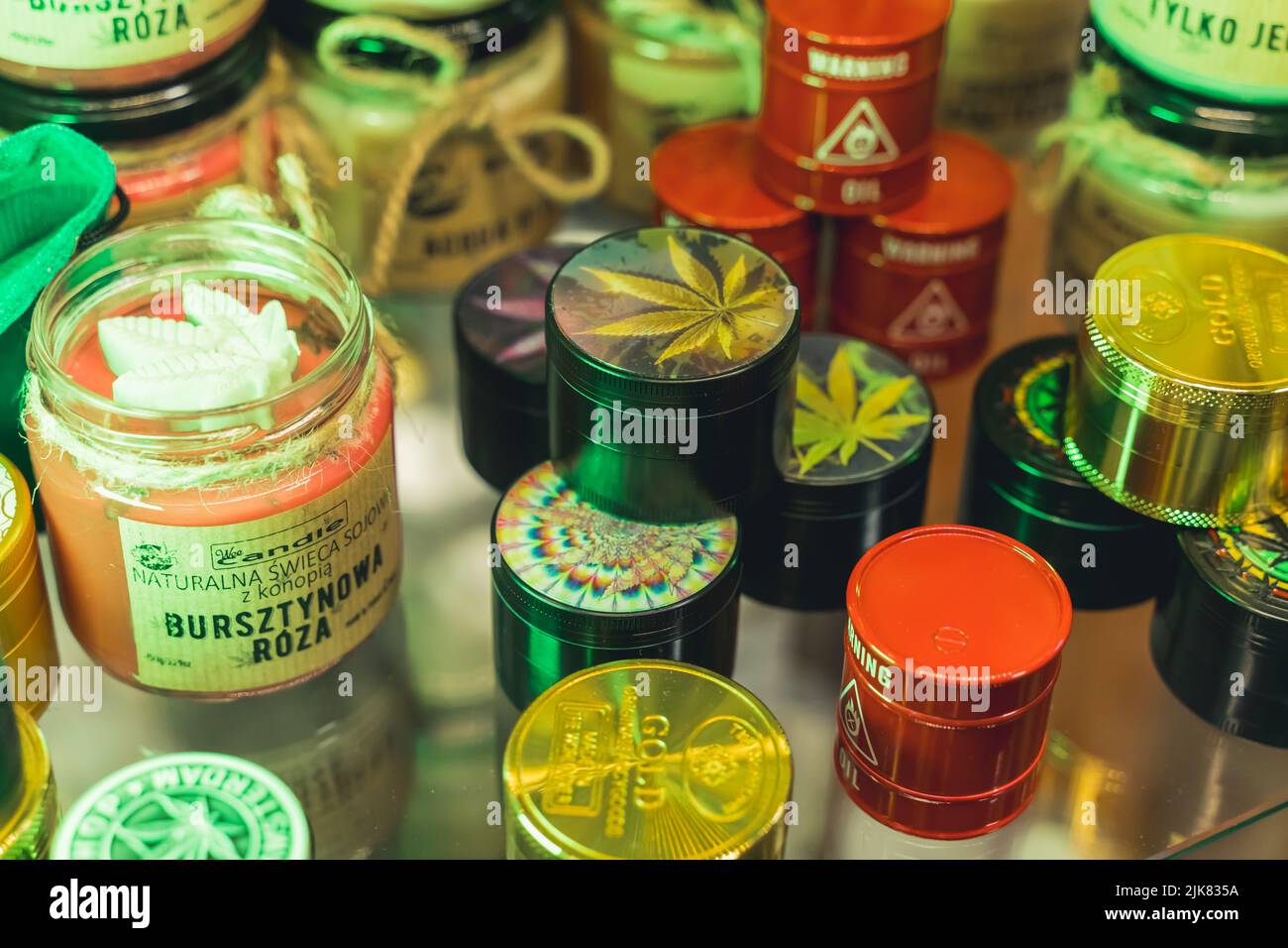 05.28.2022 Varsavia, Polonia. Scatole di stoccaggio colorate per crashers o germogli di marijuana medica insieme a una candela di canapa in piedi su un display in vetro. Foto di alta qualità Foto Stock