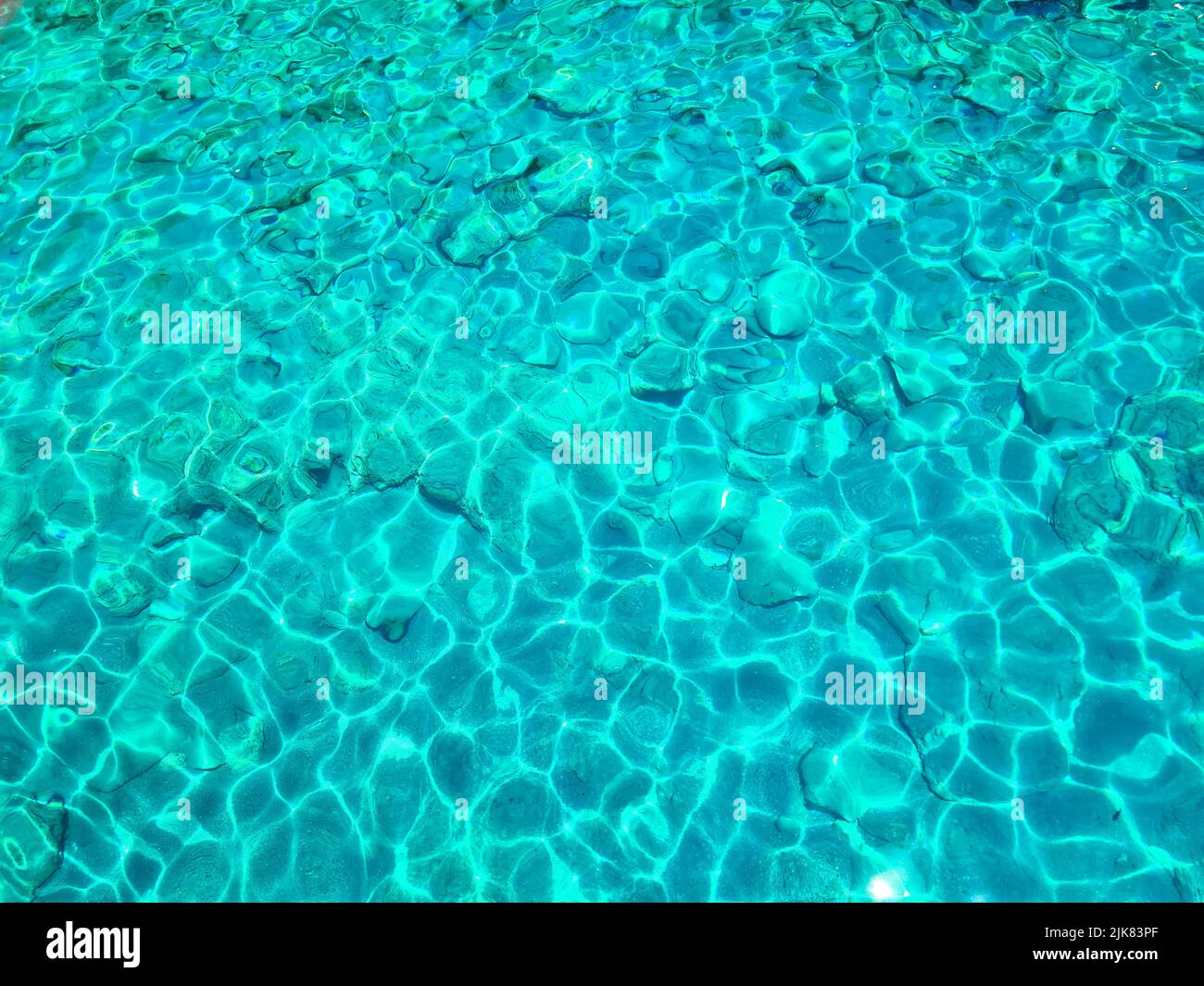 Superficie turchese di acqua di mare trasparente con sdraie al sole Foto Stock