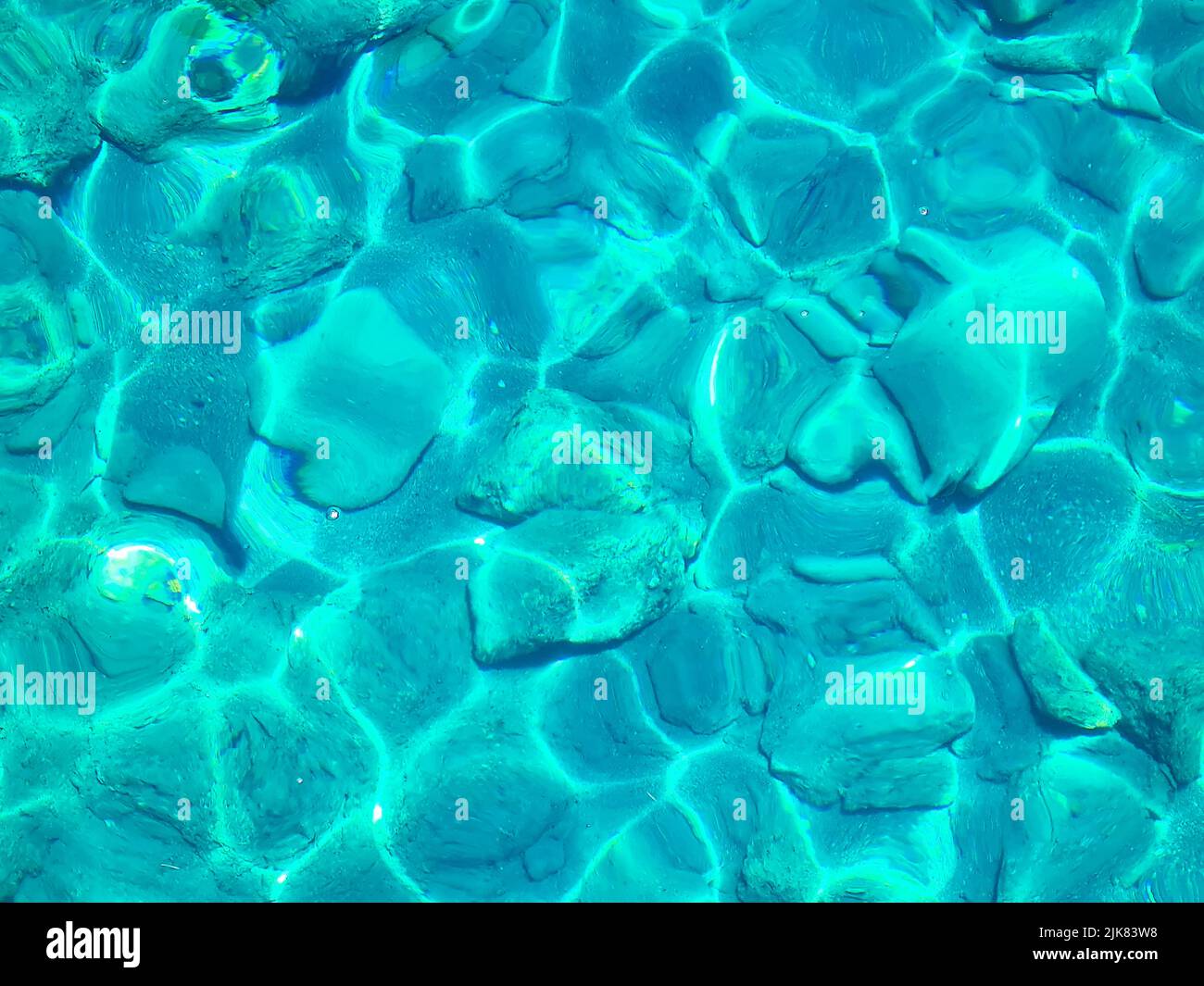 Superficie turchese di acqua di mare trasparente con sdraie al sole Foto Stock