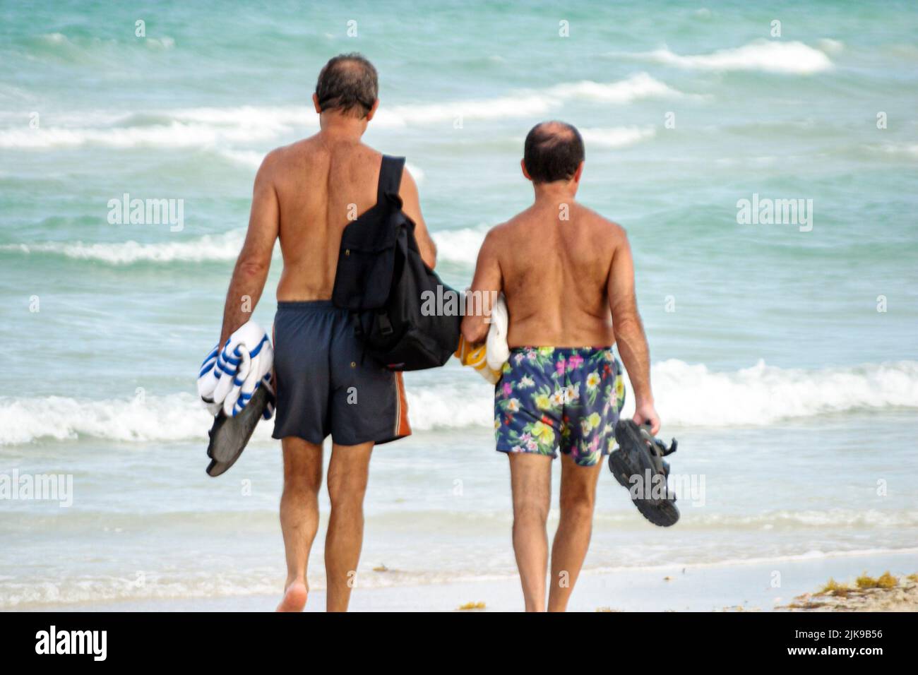 Miami Beach Florida,Atlantic Shore Ocean Shoreline Coast litorale spiaggia, due uomini 2 uomini uomo spiaggia pettinatori amici camminare indossando costumi da bagno Foto Stock