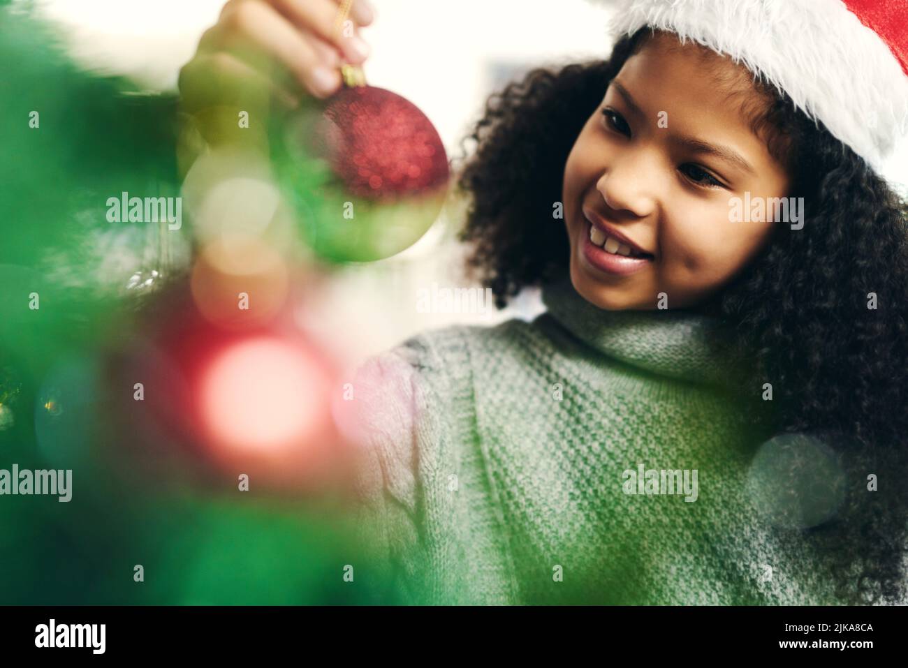 Santas piccolo aiutante ha preso la giornata fuori così sono qui. Una ragazza piccola carina che decora un albero di Natale a casa. Foto Stock