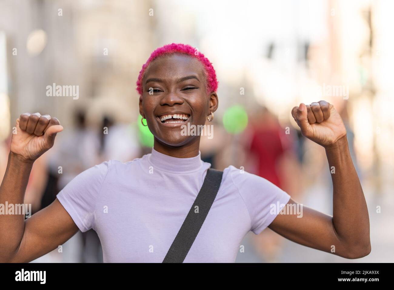 Felice giovane donna africana che alza le armi in città Foto Stock