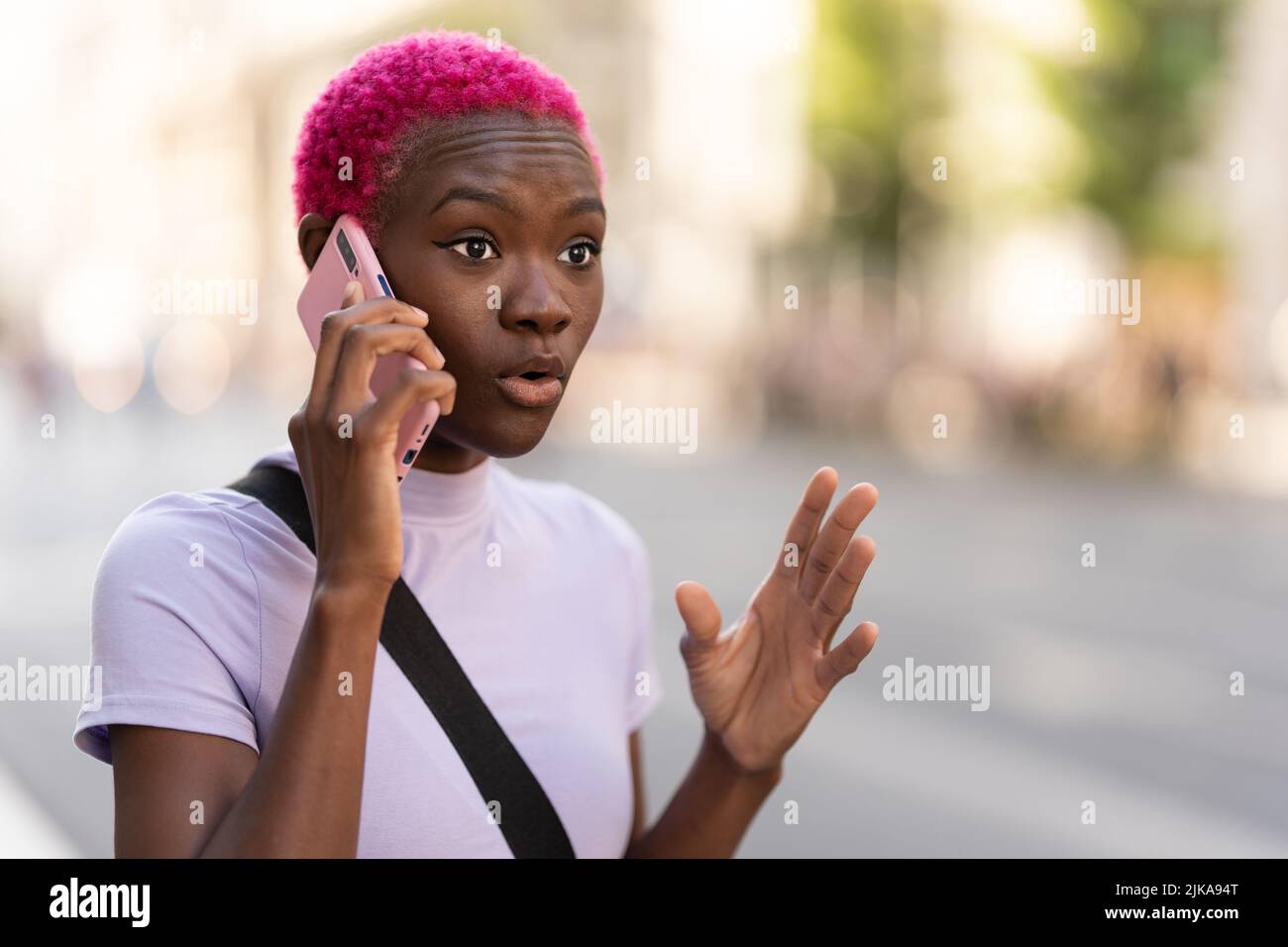 Giovane donna africana che parla energicamente sul suo mobile all'aperto Foto Stock