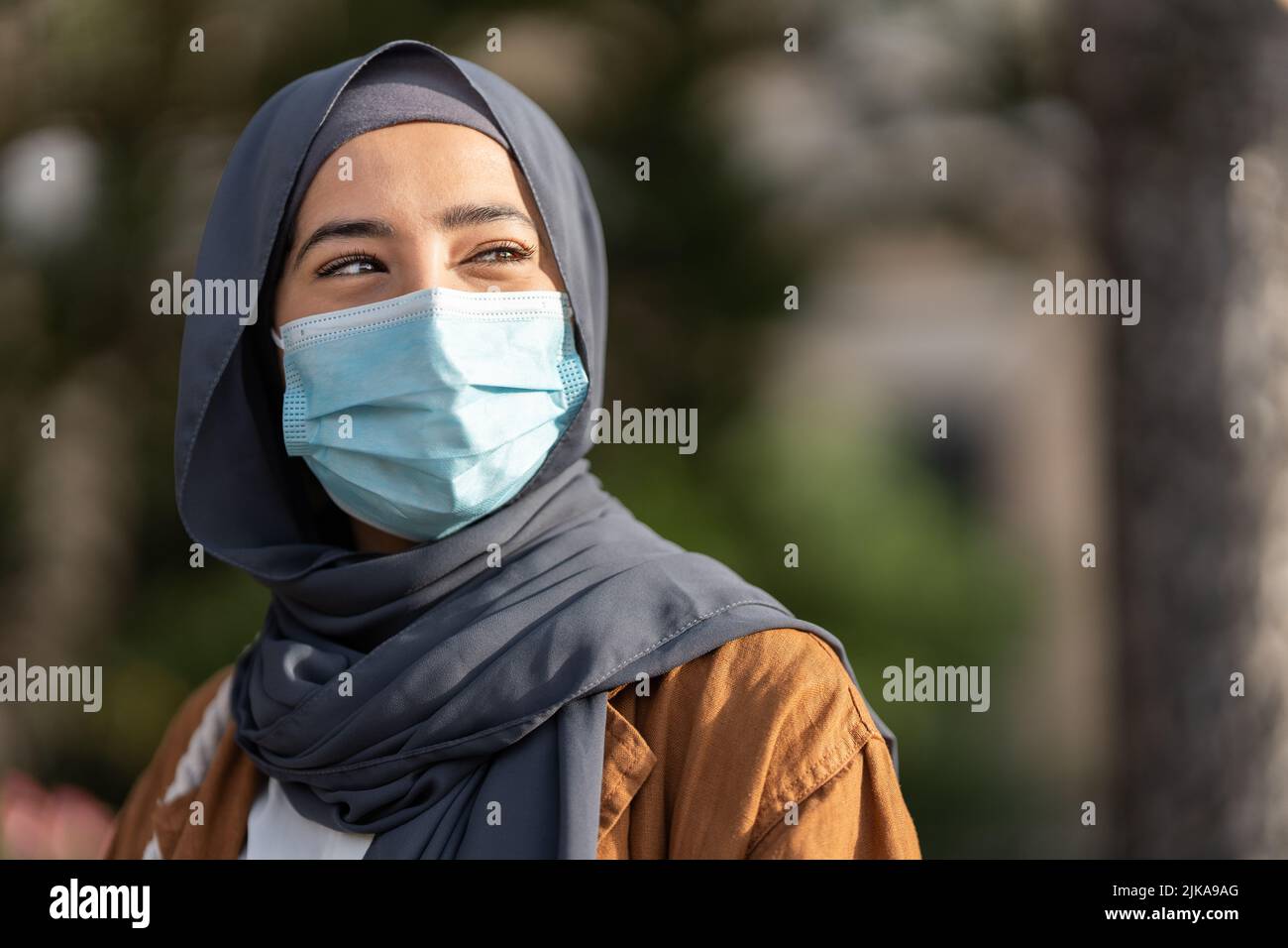 Donna musulmana che indossa maschera facciale protettiva all'aperto Foto Stock