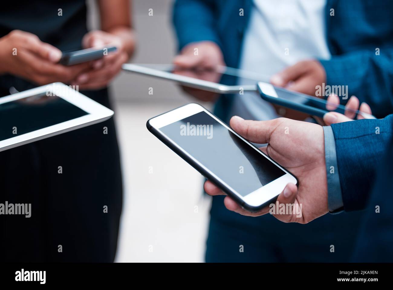 Insieme, ancora da solo. Un gruppo di uomini d'affari irriconoscibili che utilizzano i loro dispositivi mobili. Foto Stock