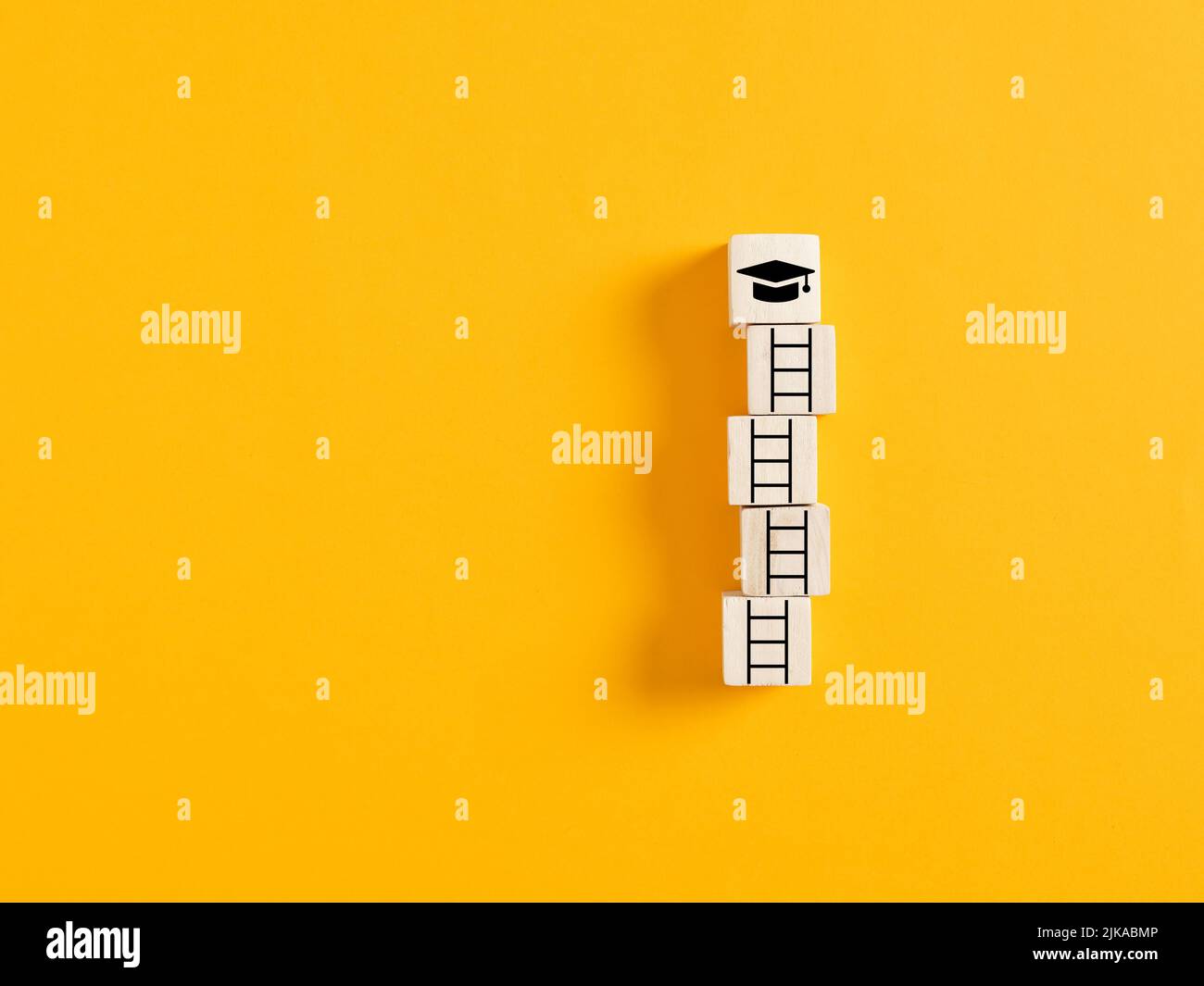 Scala di successo con cubetti di legno e cappuccio di graduazione accademica. Raggiungere il concetto di istruzione, laurea e obiettivi di conoscenza. Foto Stock