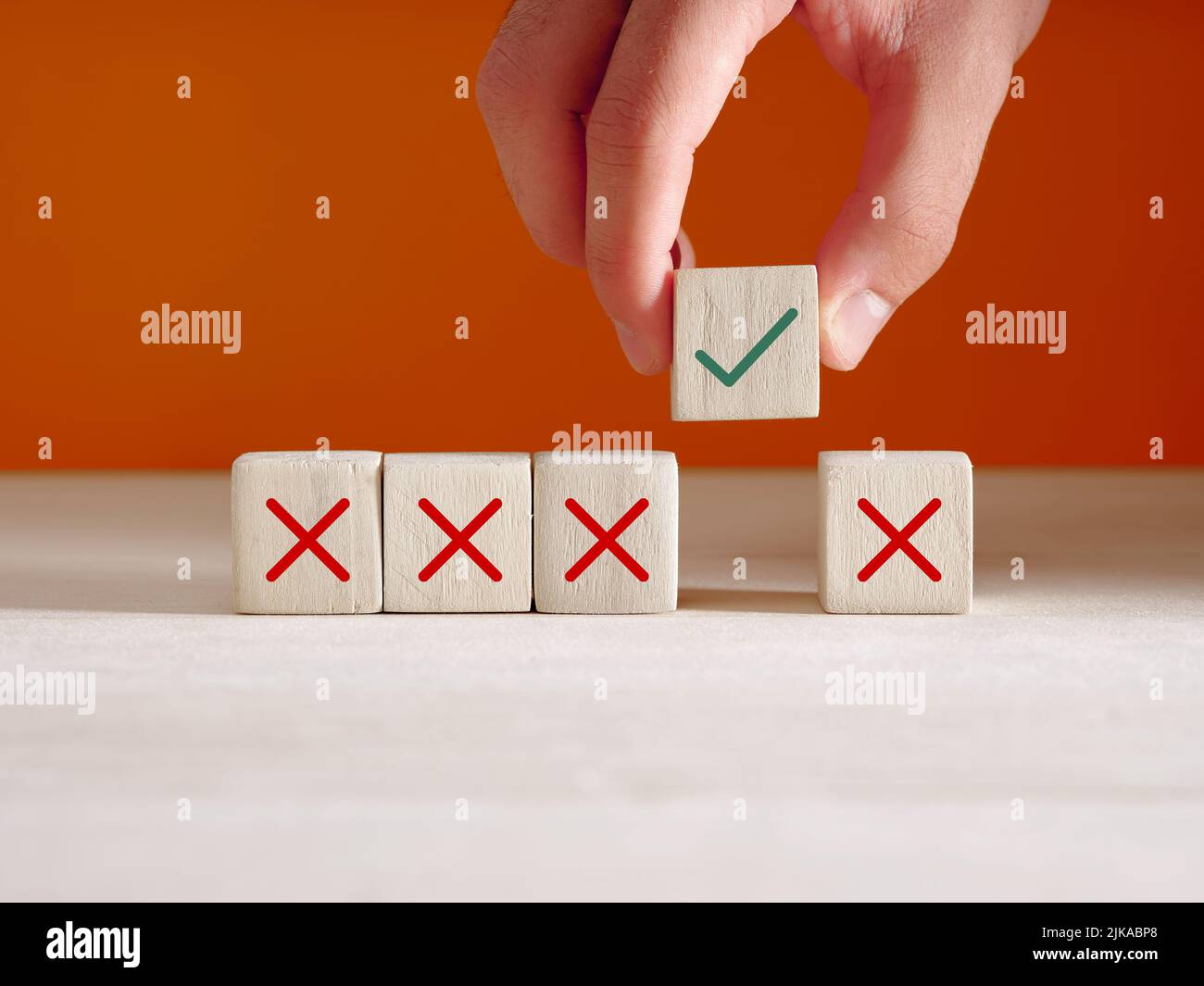 Approvazione o scelta dell'opzione giusta per il concetto di startup aziendale. Mano mette il cubo di legno con l'icona destra accanto ai cubi con icone errate. Foto Stock
