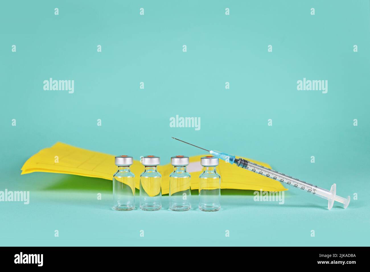 Corona Booster Vaccine Concept con 4 flaconcini con siringhe e certificato di vaccinazione in background con spazio di copia Foto Stock