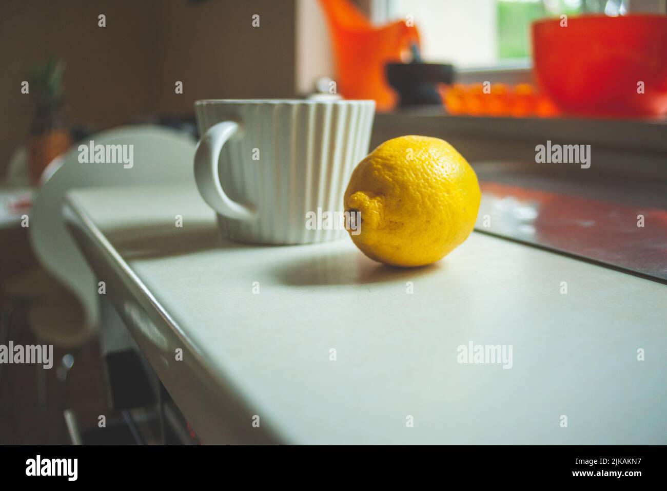 Una tazza e un limone sul piano di lavoro Foto Stock