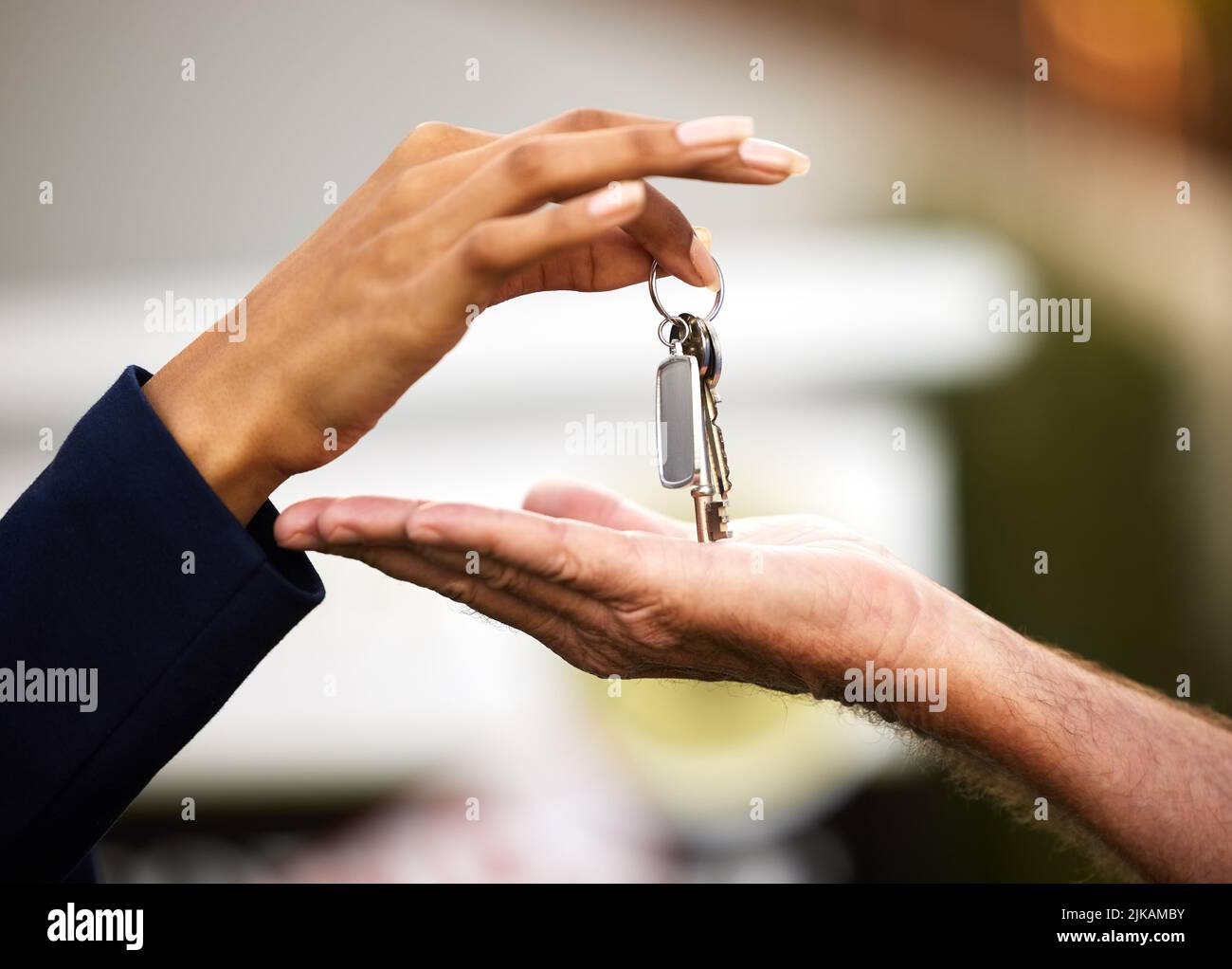 Consegnare le chiavi è l'ultima cosa da fare. Un agente immobiliare femminile irriconoscibile che consegna le chiavi di una casa appena acquistata al suo maschio Foto Stock