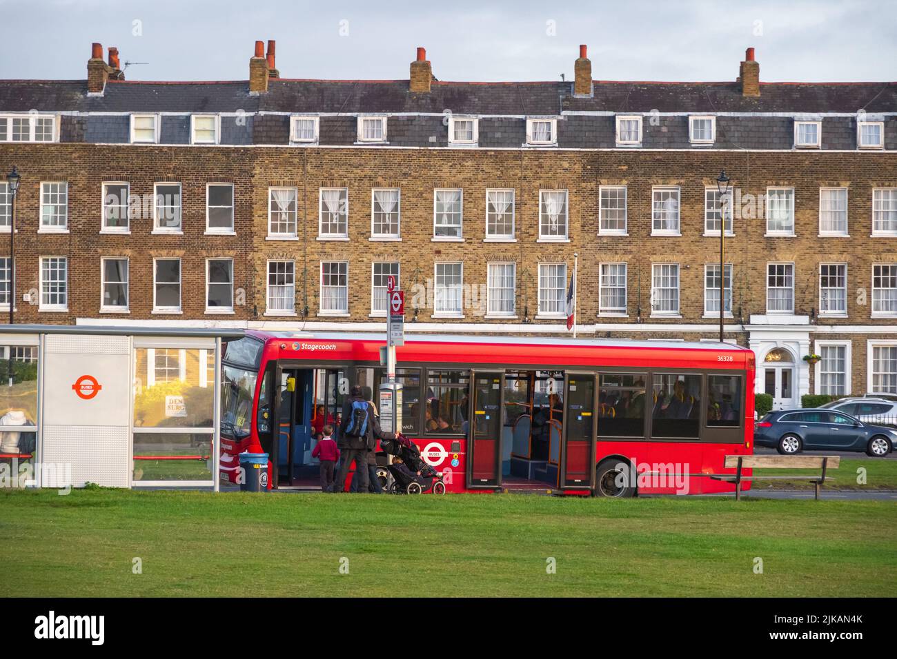 Londra, Regno Unito - 3 novembre 2021 - i passeggeri che salpano a bordo dell'autobus intorno a Blackheath con una casa a schiera georgiana sullo sfondo Foto Stock