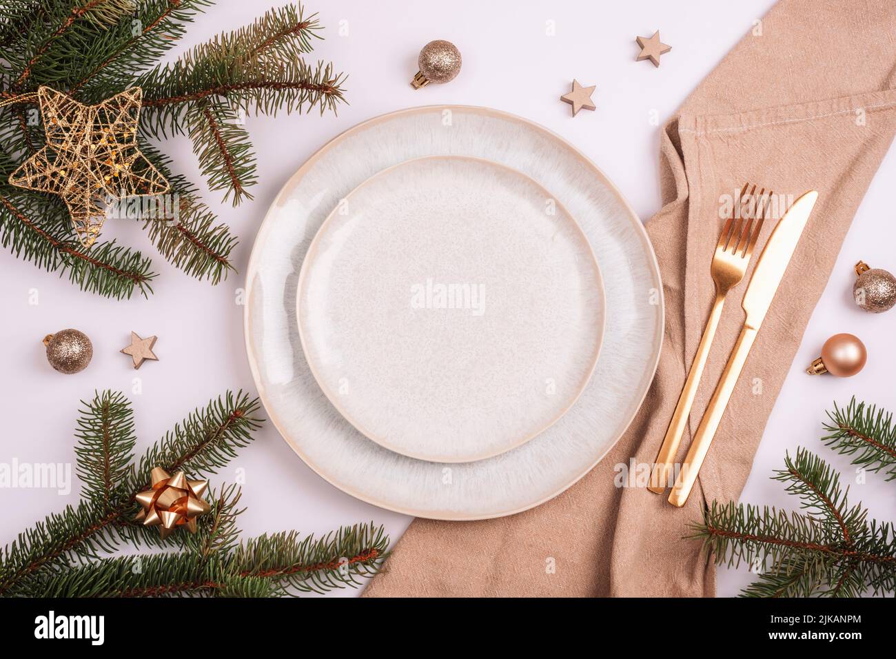 Tavolo elegante, rami di abete, stella e palle con piatto bianco, posate e tovagliolo beige su tavola bianca. Concetto di Natale. Vista dall'alto, piatto Foto Stock