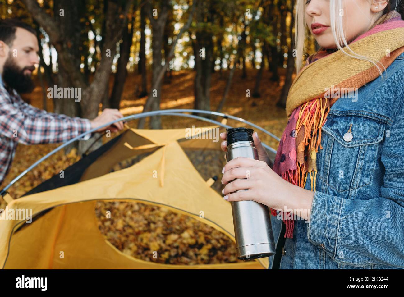 autunno campeggio natura parco uomo tenda donna thermos Foto Stock