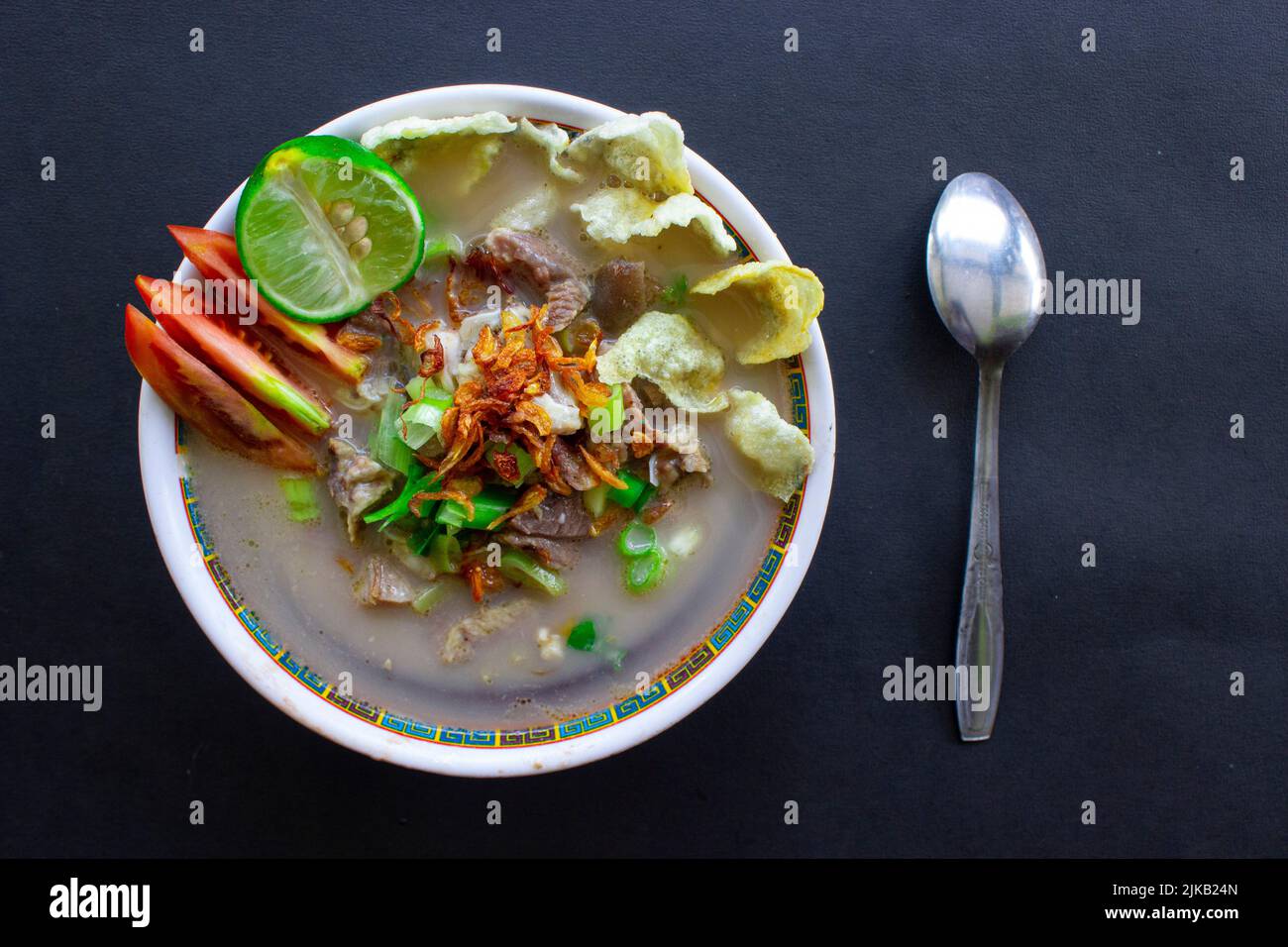 sop kaki Kambing un cibo tradizionale da Betawi, Jakarta Indonesia, fatto di montone o agnello, frattaglie, spezie. Isolato su sfondo nero. Questo cibo Foto Stock