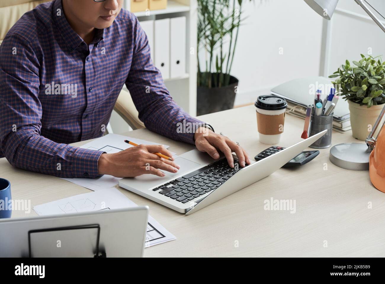 Progettista di immagini ritagliato che utilizza un computer portatile per comunicare con il client Foto Stock