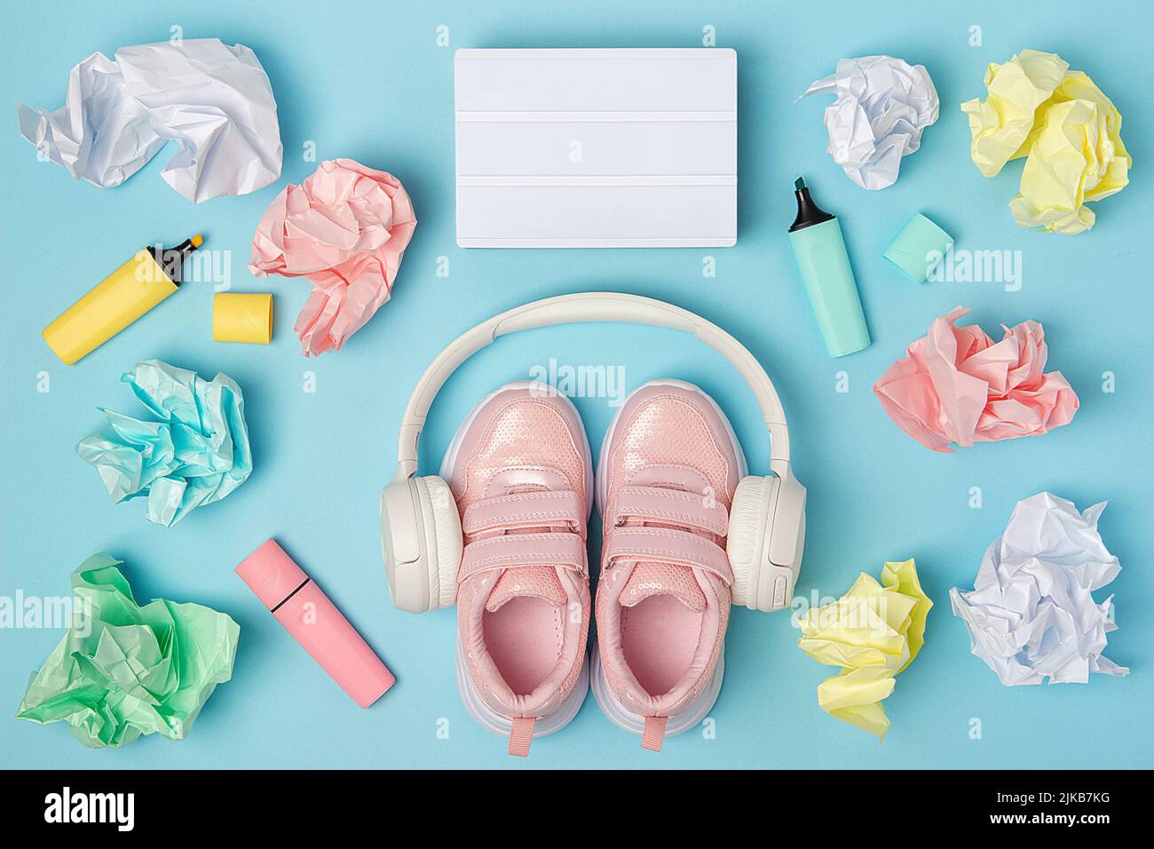 Scatola luminosa vuota. Cuffie, scarpe rosa, palline di carta colorate e sgualcite, pennarello su sfondo blu. Concetto di istruzione. Flat Lay Top View Still Life Mock Foto Stock