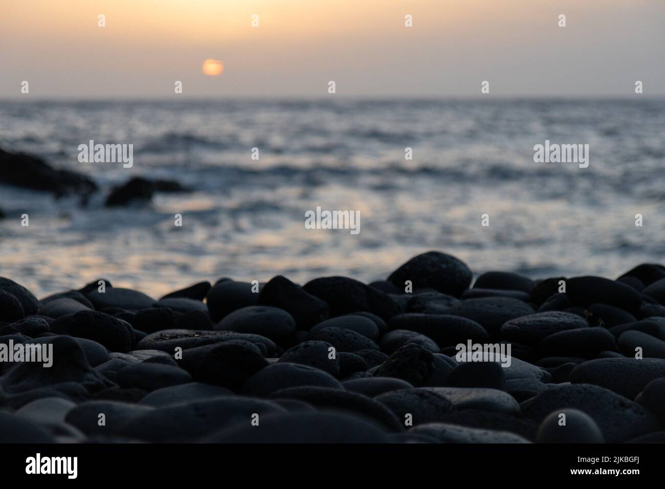 Tramonto a Tenerife. Ciottoli vulcanici neri e Oceano Atlantico. Foto Stock