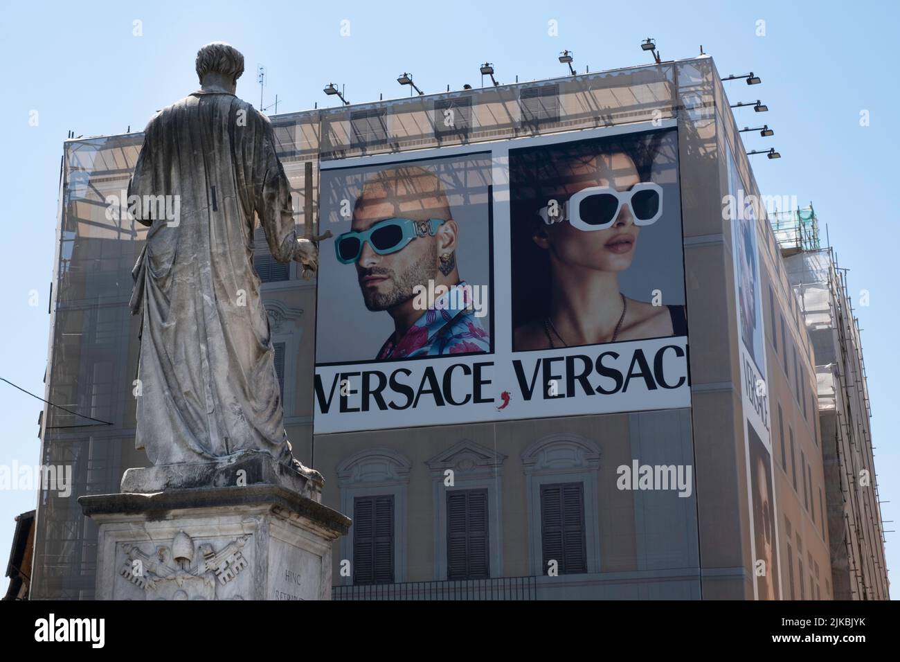 Statua dell'apostolo di San Paolo sul Ponte Sant'Angelo a Roma che si affaccia su un moderno edificio da ristrutturare con un cartellone della società di moda Versace Foto Stock