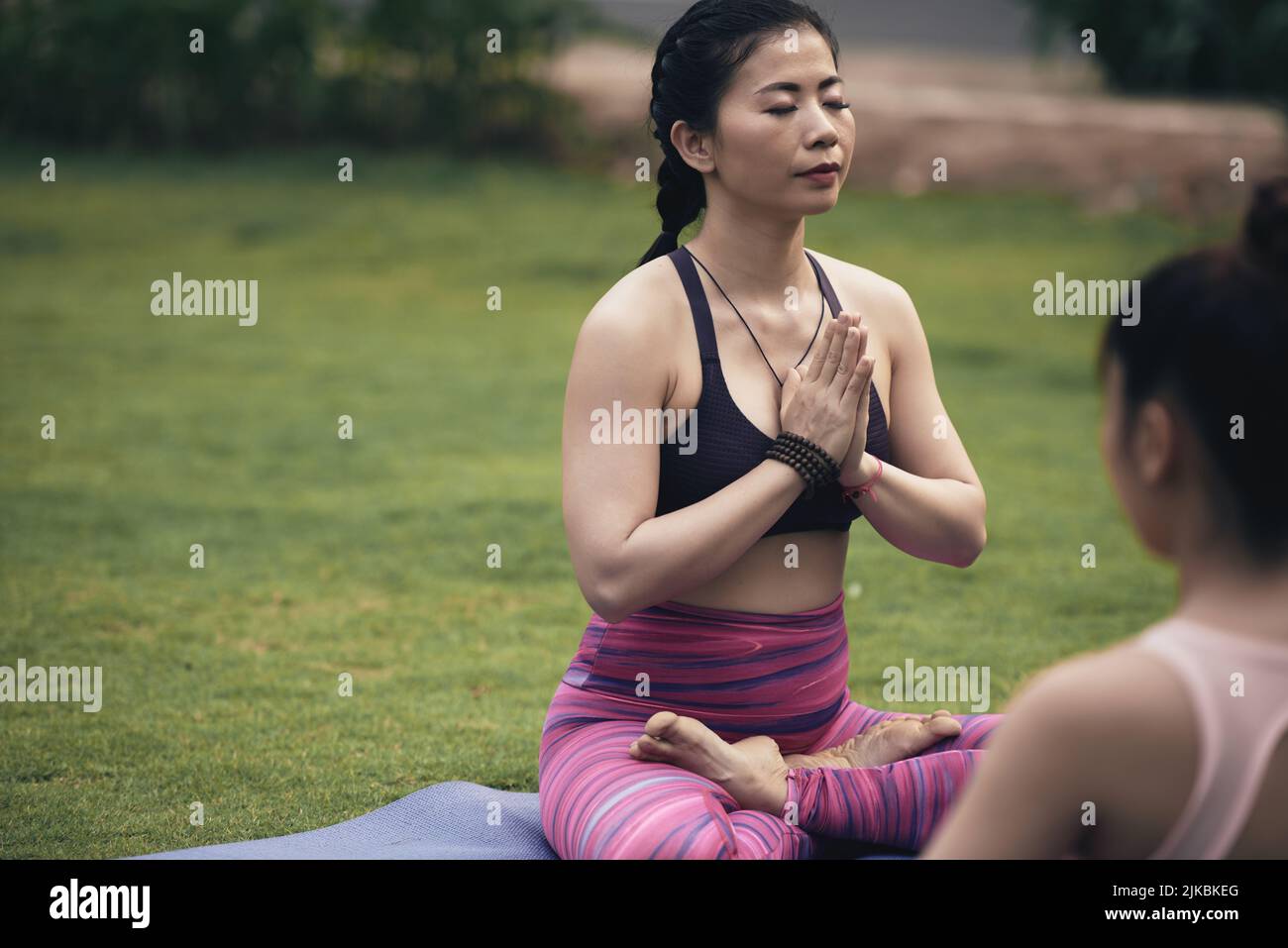 Donna vietnamita seduta in posizione lotus con gli occhi chiusi Foto Stock