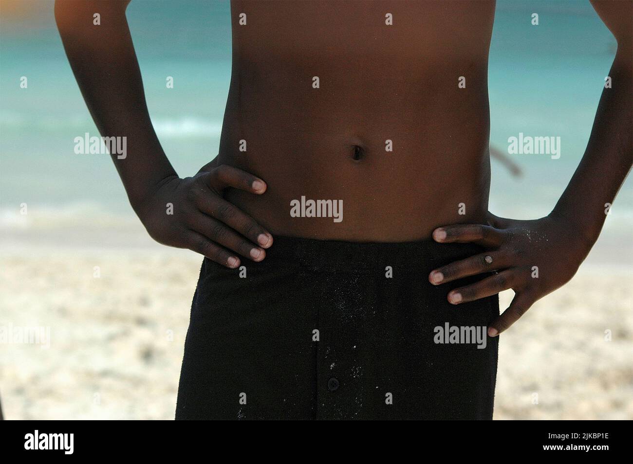 Primo piano del ventre di un giovane ragazzo messicano in un costume da bagno sulla spiaggia. Messa a fuoco selettiva Foto Stock