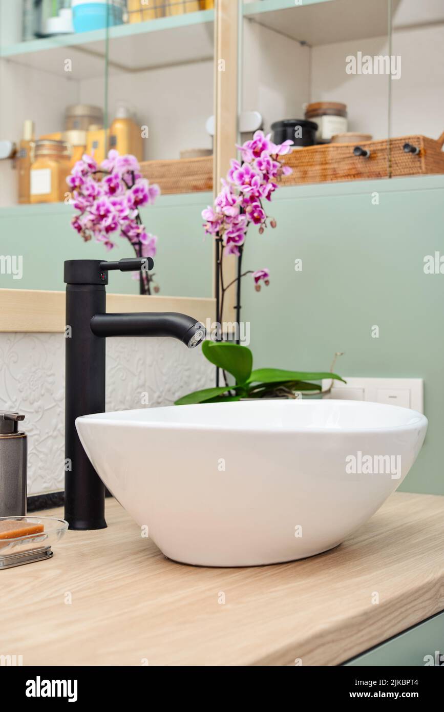 Elegante lavabo con lavabo nero sul piano di lavoro leggero in bagno moderno Foto Stock