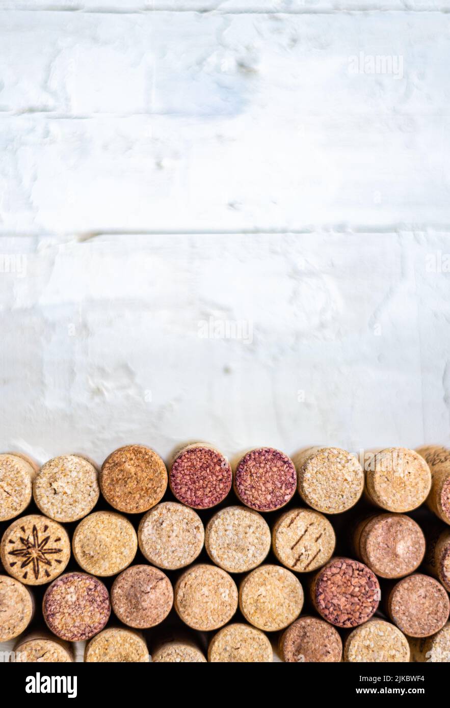 Fila orizzontale di tappi, su un tavolo bianco di legno con molto spazio negativo sopra. Utile per pubblicità su vini, enoteche, ristoranti e per v Foto Stock