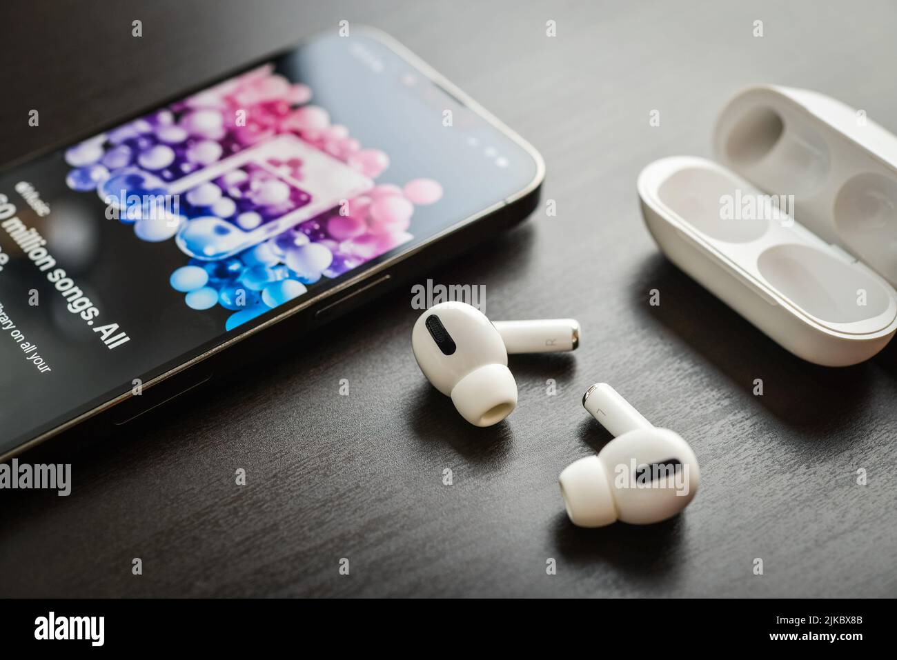 KIEV, UCRAINA - 10 FEBBRAIO 2022: Custodia di ricarica e il nuovo iPhone 13 Pro con app Apple Music sullo schermo accanto a New Apple Computers AirPods Pro hea Foto Stock