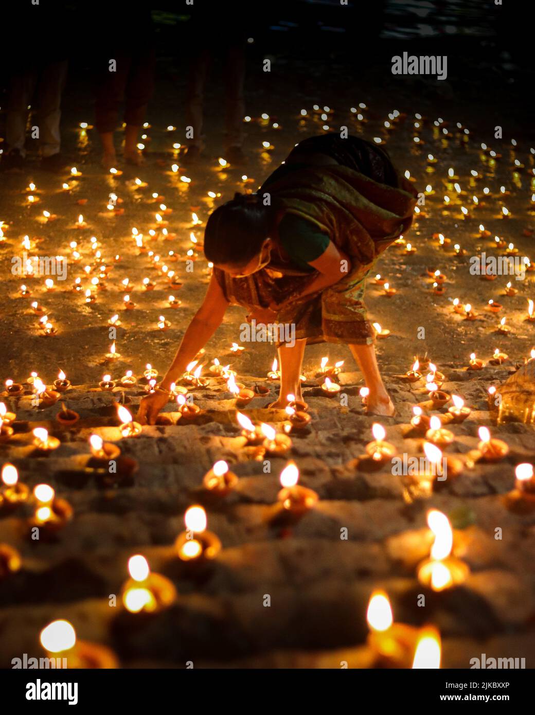 Una donna che illumina la sua candela a terra all'aperto a tarda notte Foto Stock
