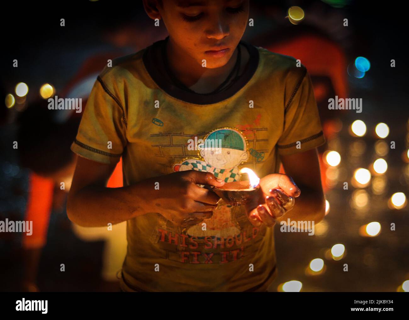 Un ragazzo che tiene una candela che brucia all'aperto a tarda notte Foto Stock