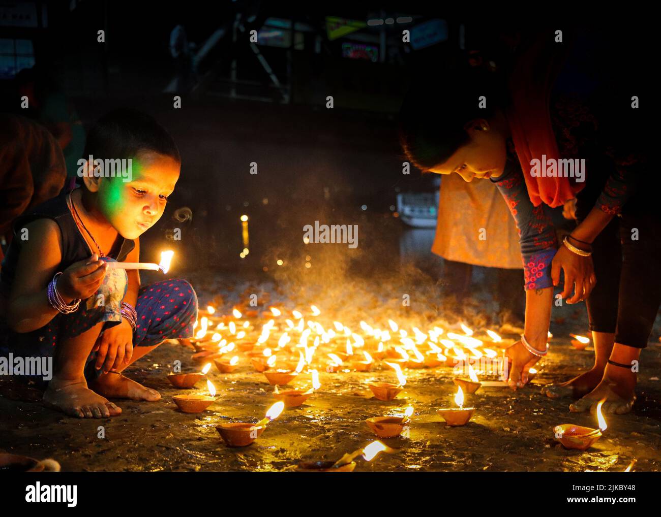 Un bambino che soffia fuori una candela che brucia all'aperto a tarda notte Foto Stock