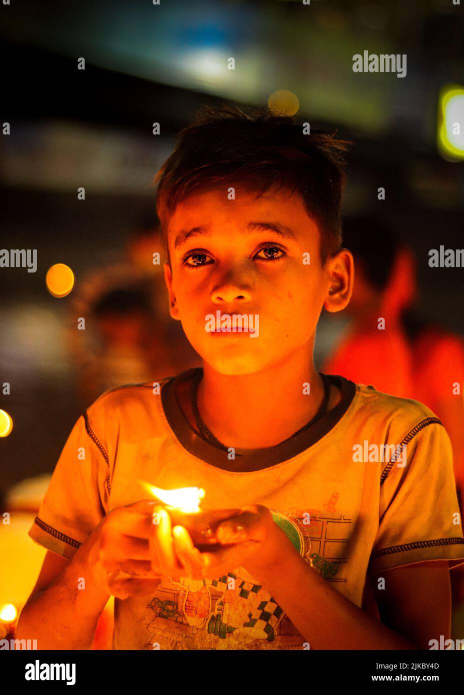 Un ragazzo che tiene una candela che brucia all'aperto a tarda notte Foto Stock
