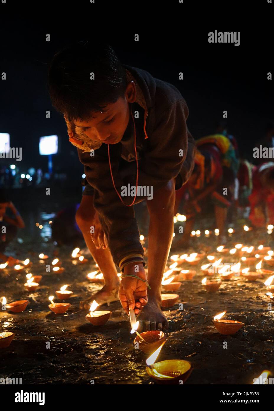 Un ragazzo che illumina la sua candela a terra all'aperto a tarda notte Foto Stock