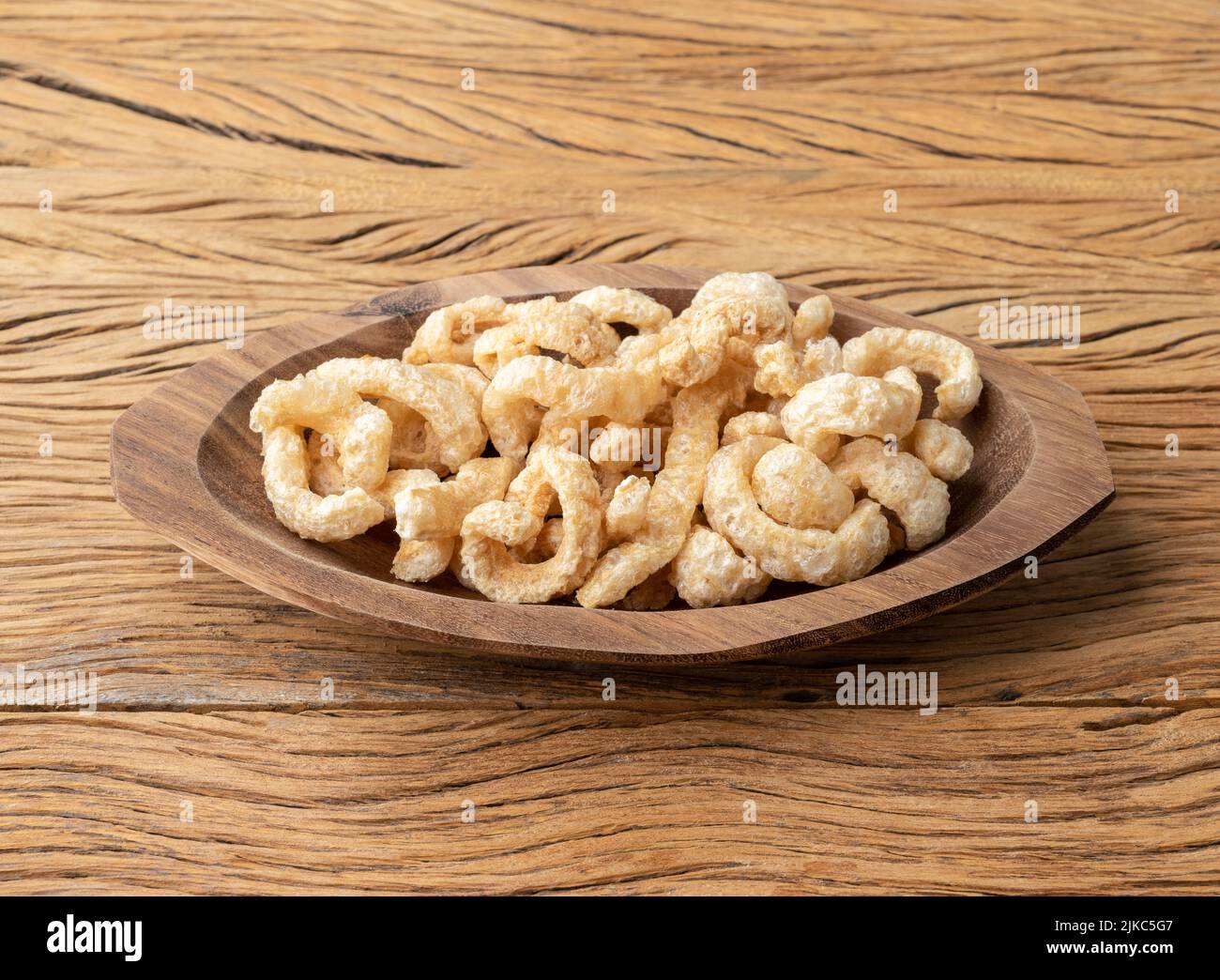 Crackling di pelle di maiale fritto su un piatto su tavola di legno. Foto Stock