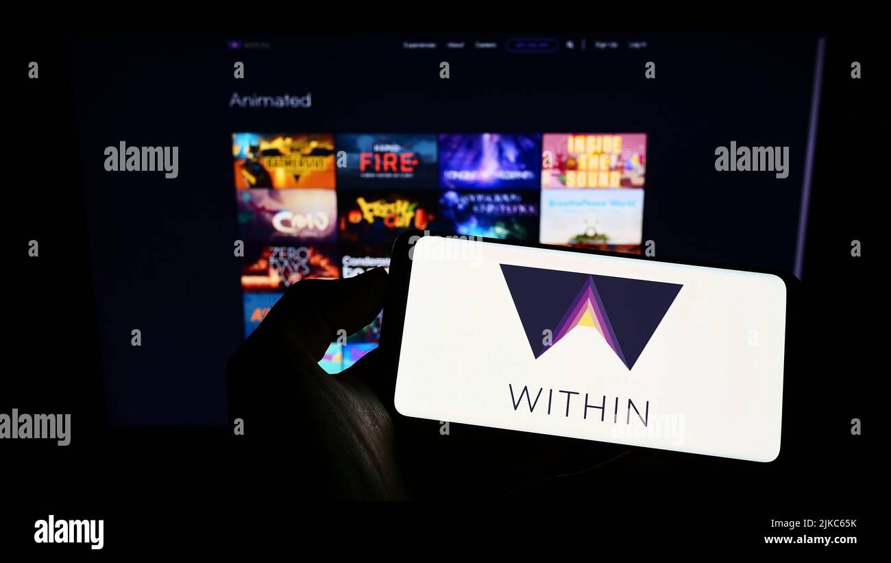 Persona che tiene il cellulare con il logo della società di realtà virtuale degli Stati Uniti all'interno di Unlimited Inc. Sullo schermo di fronte al sito web. Mettere a fuoco sul display del telefono. Foto Stock
