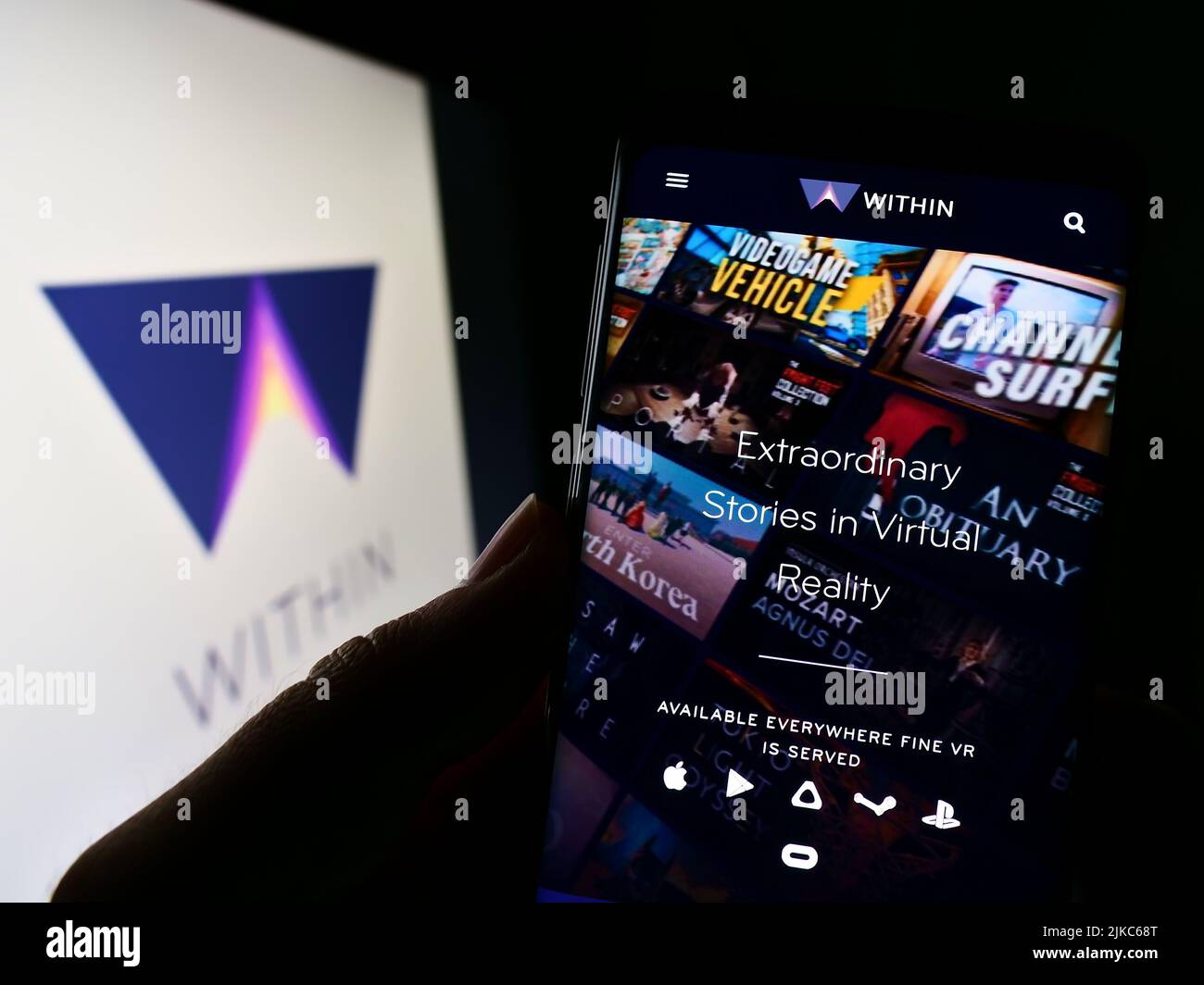 Persona che tiene il cellulare con il sito web della società di realtà virtuale all'interno di Unlimited Inc. Sullo schermo con il logo. Concentrarsi sul centro del display del telefono. Foto Stock