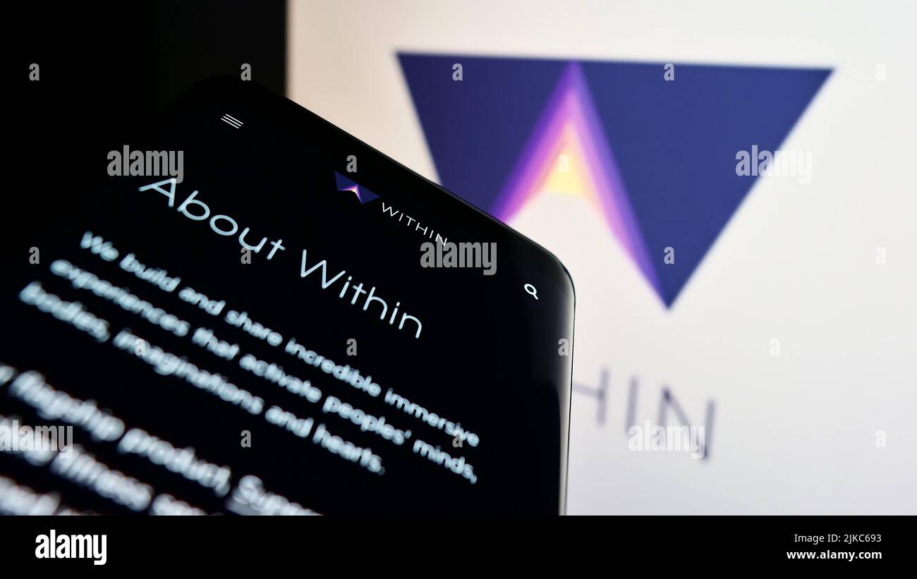 Telefono cellulare con pagina web della società americana di realtà virtuale all'interno di Unlimited Inc. Sullo schermo di fronte al logo. Mettere a fuoco sulla parte superiore sinistra del display del telefono. Foto Stock