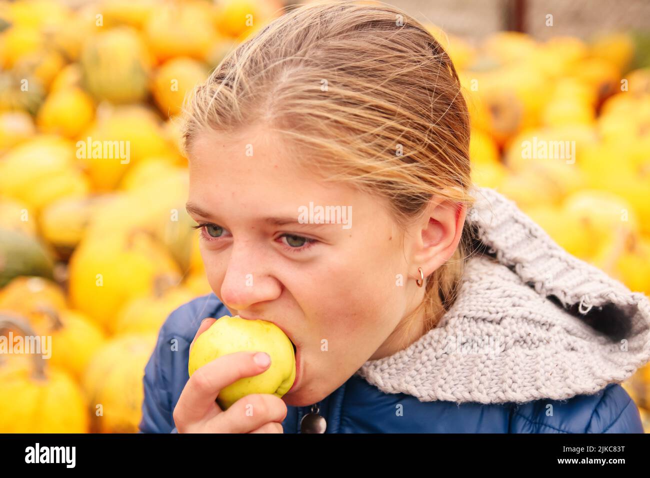 Defocus triste depresso giovane ragazza adolescente seduta fuori su sfondo giallo e mangiare mela gialla. Scuola, adolescenza, violenza domestica, lo indesiderato Foto Stock