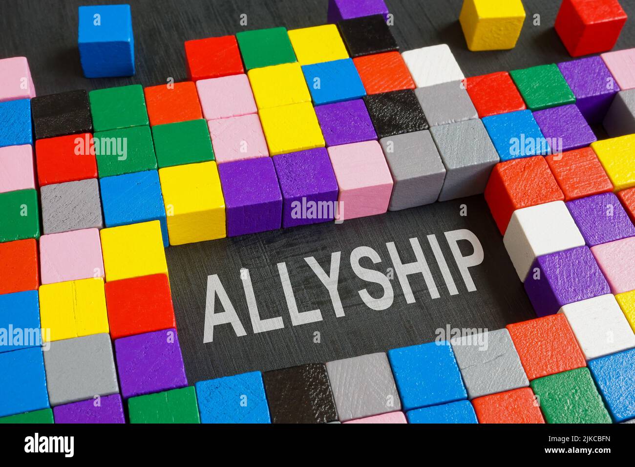 Parola allyship e cubi colorati sulla superficie scura. Foto Stock