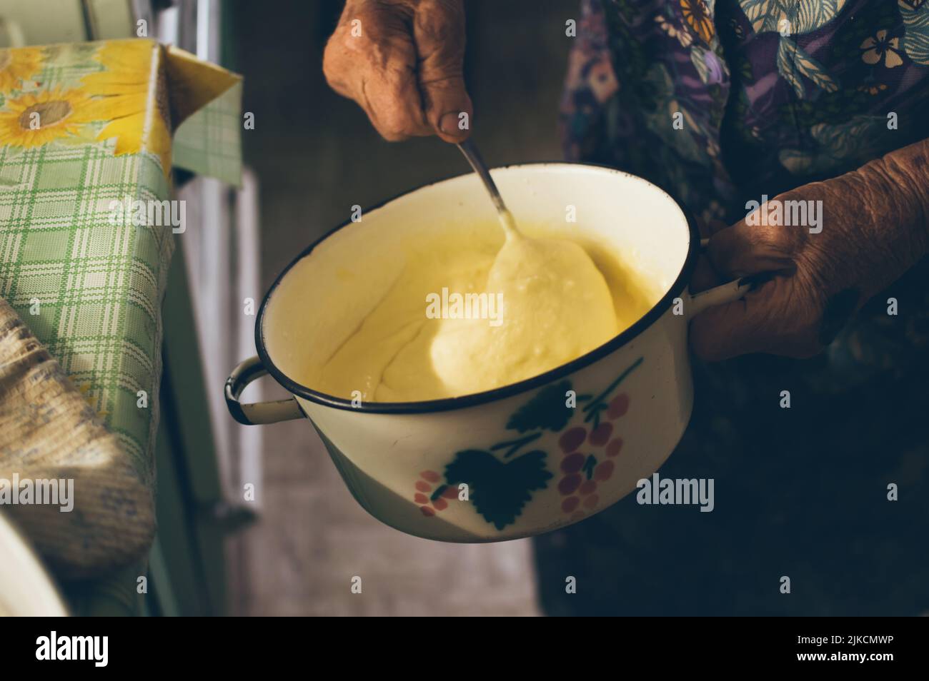 La nonna vecchia impasta per frittelle in pentola Foto Stock