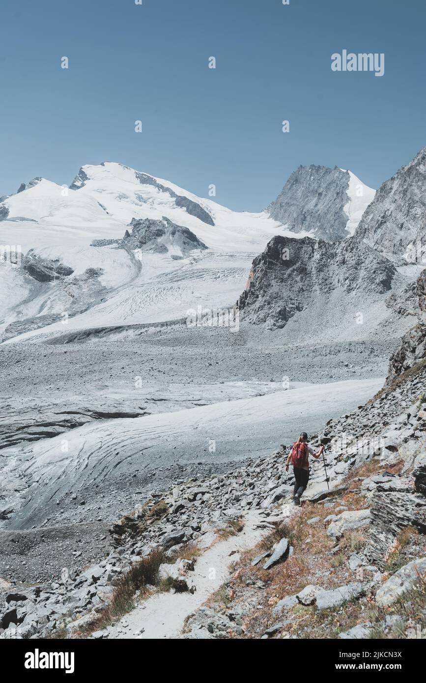 Immagine verticale dell'escursionista dalla schiena che cammina verso ghiacciai e cime Foto Stock