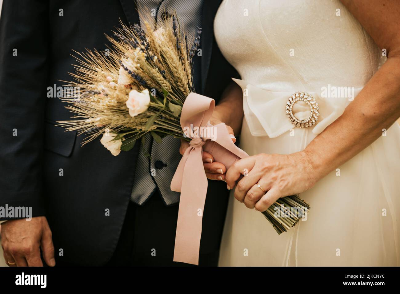 Mani di un nuovo, mentre la sposa tiene il bouquet della cerimonia Foto Stock