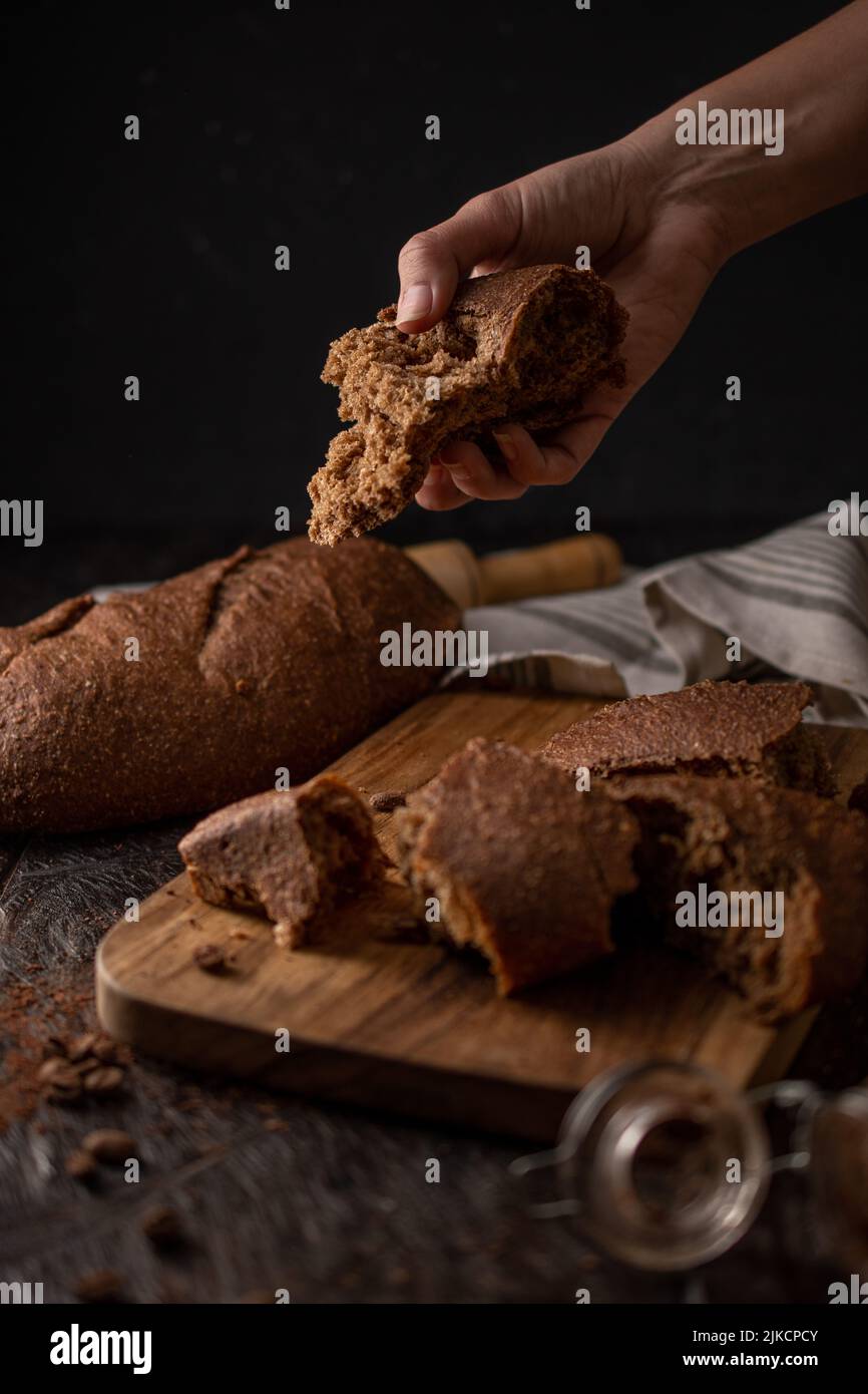 DARK PHOTOGRAPHY DE PAN ARTESANAL CON MANO EN ACCION Foto Stock