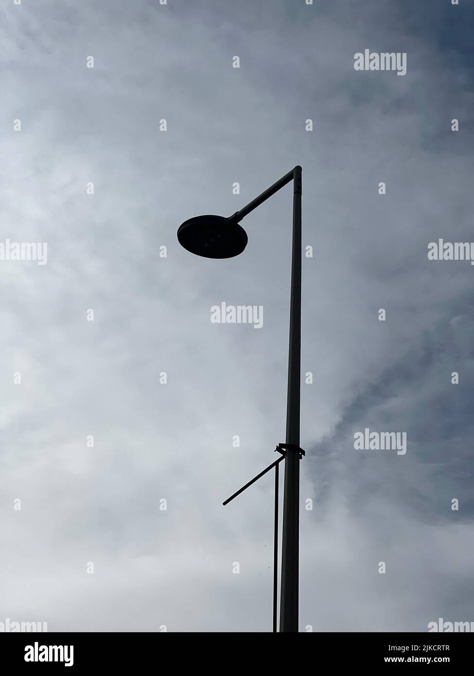 Un'immagine verticale a basso angolo di un singolo lampione in una giornata nuvolosa con un bel cielo sullo sfondo Foto Stock