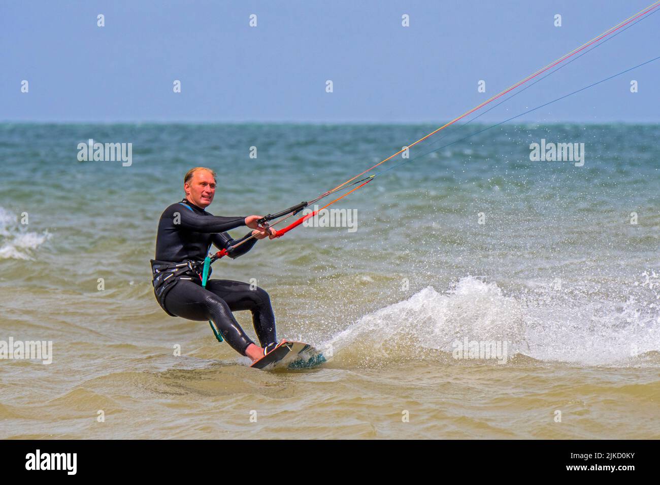 Kiteboarder / kitesurfer indossare muta su tavola doppia kitesurf sul Mare del Nord Foto Stock