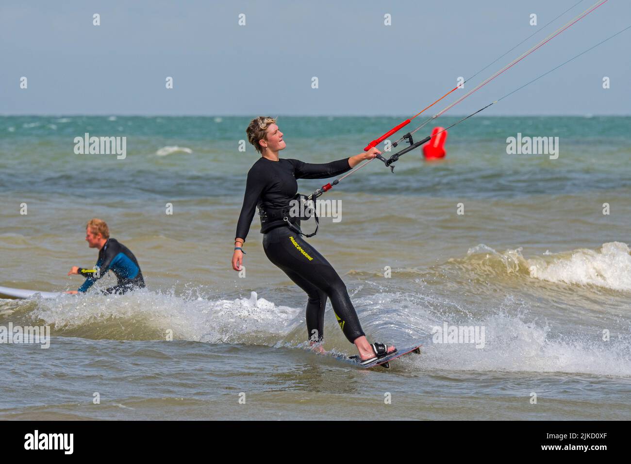 Kiteboarder femminile / kitesurfer indossare muta su tavola doppia kitesurf sul Mare del Nord Foto Stock