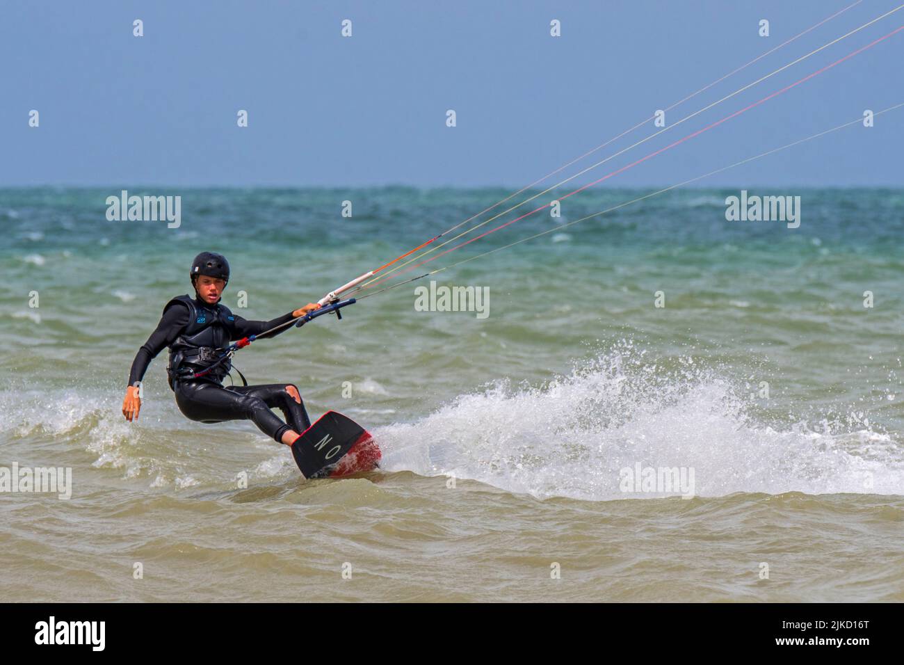 Kiteboarder giovane / kitesurfer indossare muta su tavola doppia kitesurf sul Mare del Nord Foto Stock
