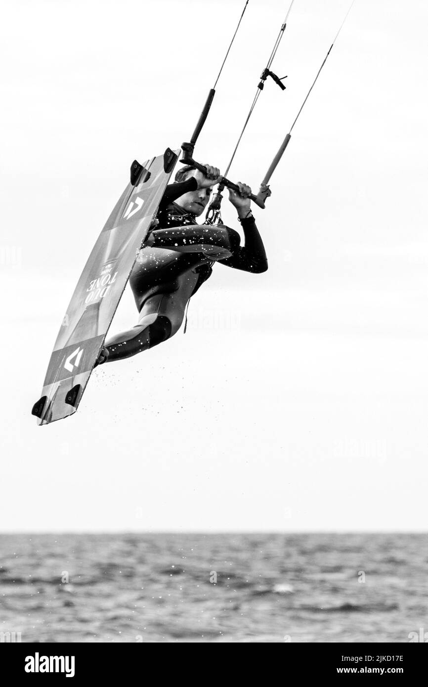 Kitesurf mostra kiteboarder / kitesurfer sulla tavola a punta doppia saltando sul Mare del Nord in una giornata ventosa Foto Stock