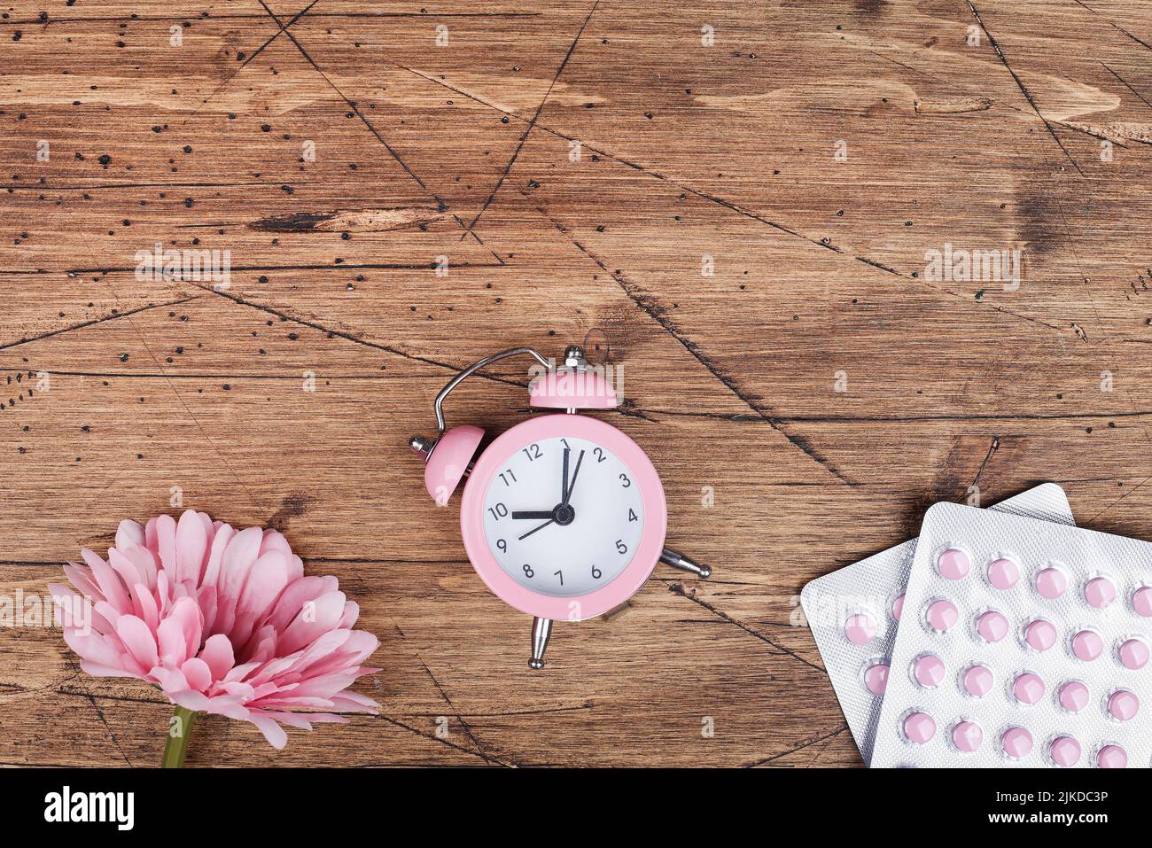 concetto di salute delle donne. spazio copia. pillole, fiori e orologio su sfondo di legno marrone. benessere, medicina, salute personale e fisica. Foto Stock